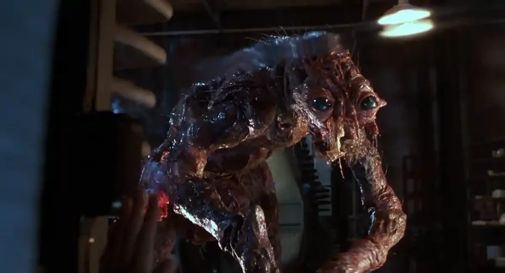 Criatura monstruosa y completamente mutada, con ojos de insecto y cuerpo deforme, escena final de la película La mosca.