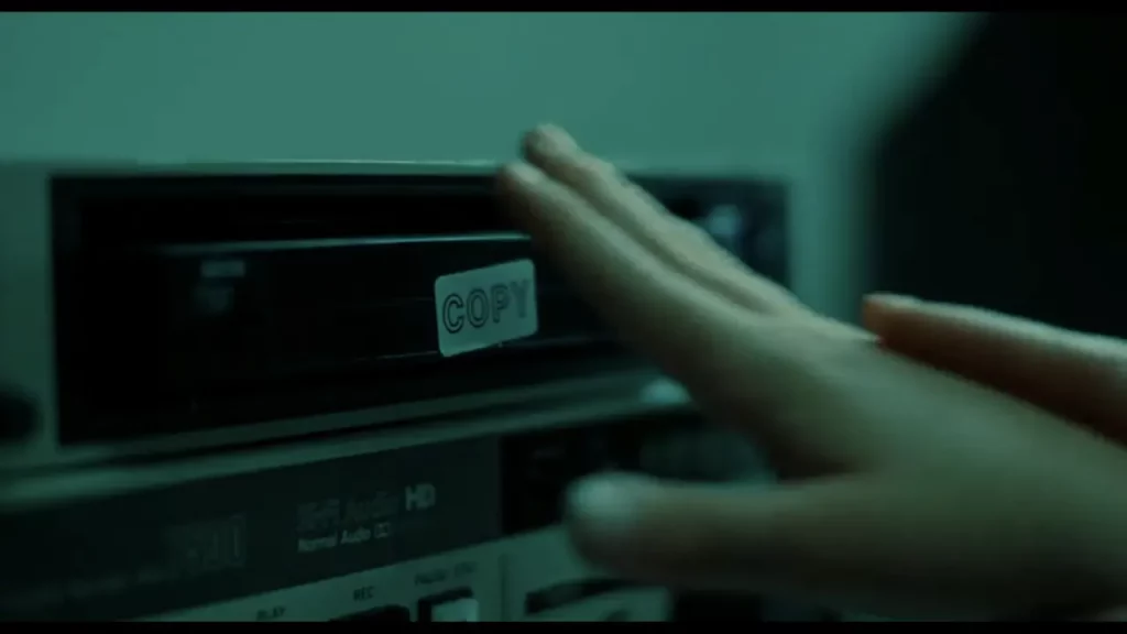 Mano acercándose a una cinta de vídeo etiquetada con la palabra “COPY”.