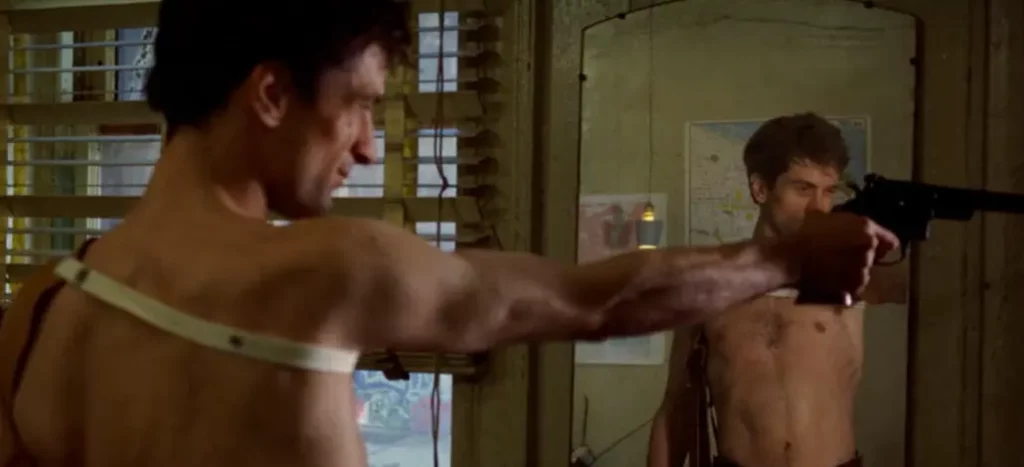 Travis Bickle apuntándose con un arma frente al espejo en Taxi Driver, representando el conflicto interior y la psicologización del mito en el cine moderno.